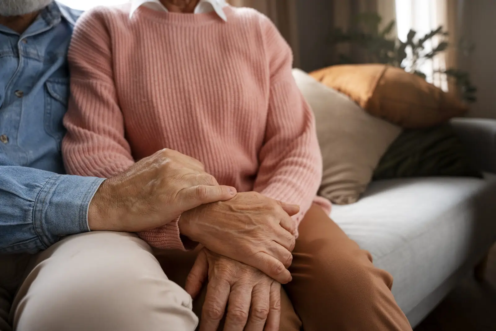 Älteres Paar hält sich auf dem Sofa an den Händen, Unterstützung für Angehörige bei Demenz