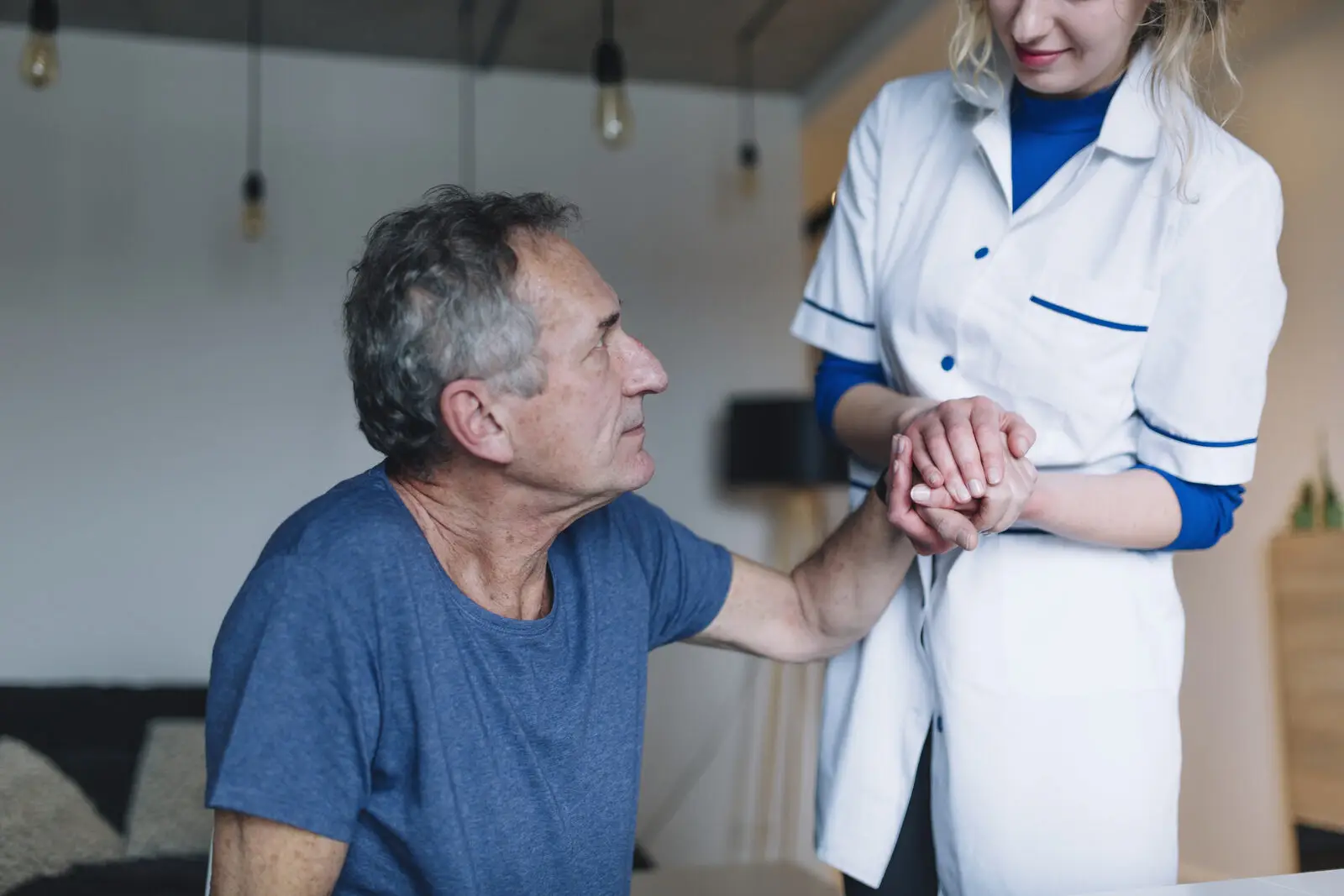 Pflegerin hält die Hand eines Seniors, Unterstützung beim Pflegegrad beantragen